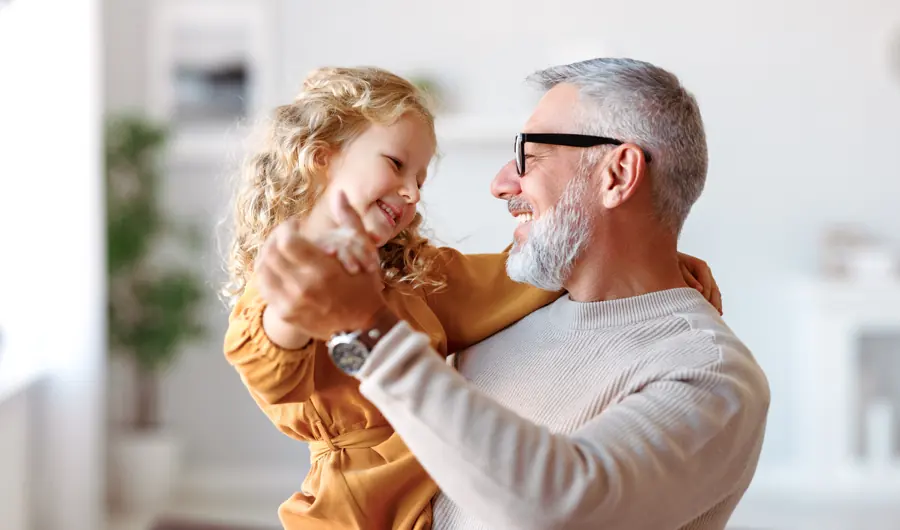 Un grand-père joue avec sa petite-fille dans un salon lumineux